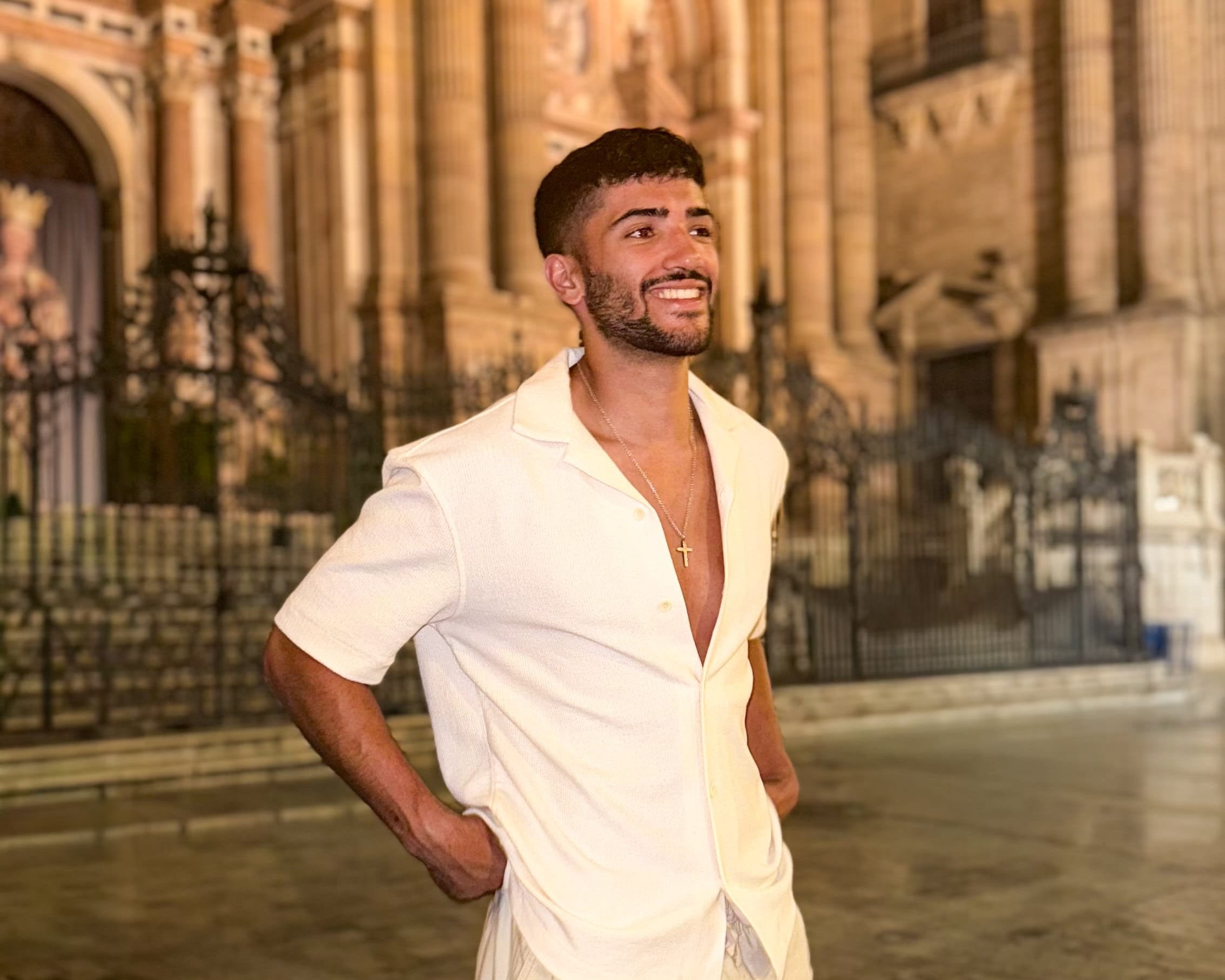 Man in a white outfit standing in front of a historic building